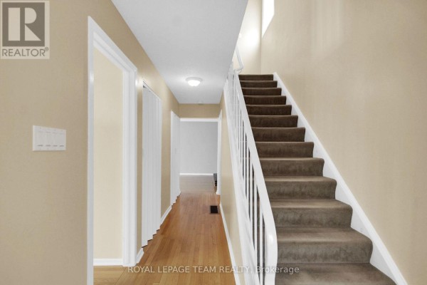 Interior hallway with hardwood floors, white doors, and carpeted stairs. - 51 - 3240 Southgate Road, Ottawa