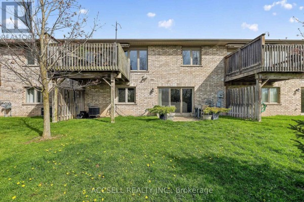 Backyard view of townhouses with wooden decks, grass, and fence. - 51 - 765 Killarney Road, London North