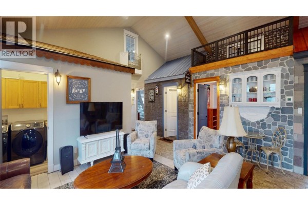 Living area with a sofa, armchair, kitchen, dining table, and a large plant. - 51 103 Avenue, Kimberley