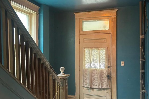 Interior view of a hallway with blue walls, a wooden staircase, and a white door. - 51 Albert Street, Carleton Place