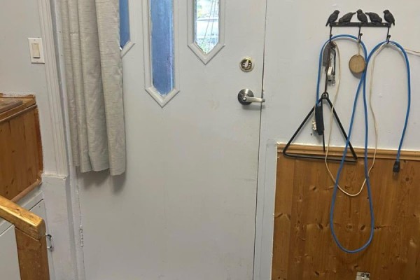 Entranceway with a light grey door, wooden paneled walls, and various items hanging. - 51 Albert Street, Carleton Place