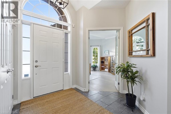 Interior view of a white front door, entryway with grey tile floor, and a doorway to a living room. - 51 Autumn Ridge Trail, Kitchener