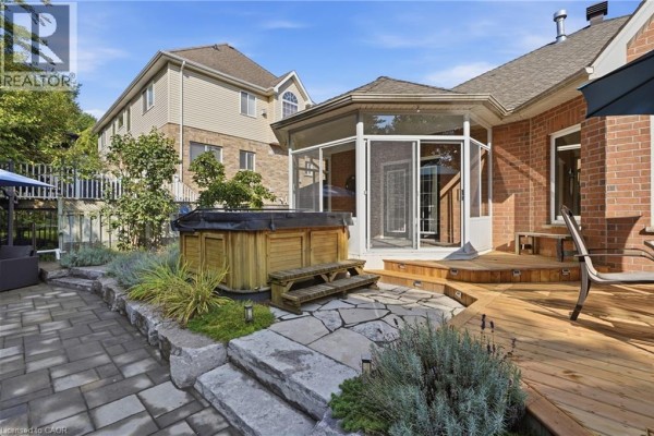 Backyard with hot tub, screened sunroom, and wooden deck - 51 Autumn Ridge Trail Kitchener