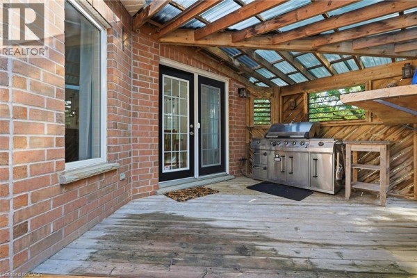 Large stainless steel grill on a wooden deck with covered patio and double doors - 51 Autumn Ridge Trail Kitchener