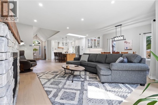 Spacious open-concept living room and kitchen with stone fireplace, sectional sofa, and skylight - 51 Autumn Ridge Trail Kitchener