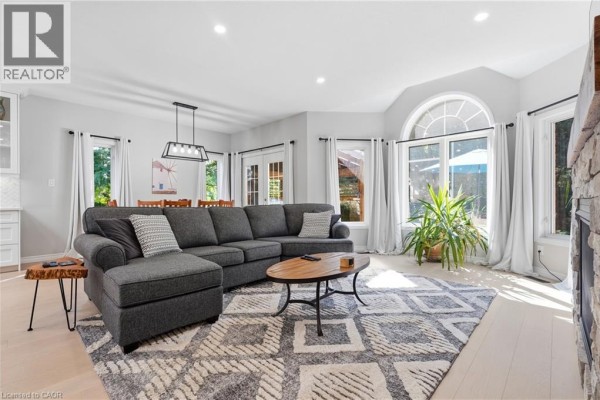 Living room with sectional sofa, stone fireplace, and large arched window - 51 Autumn Ridge Trail Kitchener