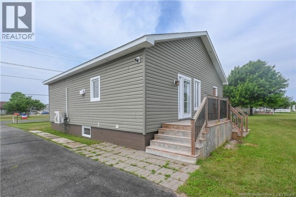 Open-concept kitchen and living area with a large island, white cabinets, and a window with blue curtains. - 51 Chiasson Road, Savoie Landing