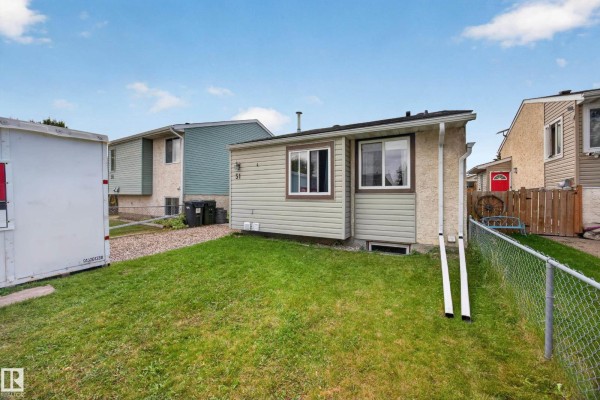 Side exterior of a light green house with brown trim and windows. Chain-link fence and grass yard. - 51 Chungo Dr, Devon