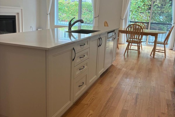 Kitchen island with white countertop, sink, and white cabinetry next to dining area. - 51 Danielle Moore Circle, Toronto
