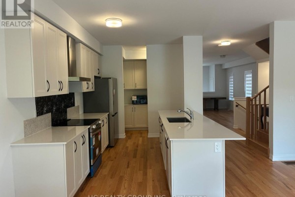 Modern kitchen with white cabinets, stainless steel appliances, and island with sink. - 51 Danielle Moore Circle, Toronto