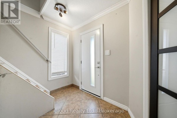 Interior foyer with beige walls, tiled floor, a white front door, and staircase. - 51 Delena Avenue S, Hamilton
