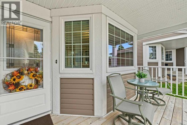 Front porch with chairs and a table, glass door with fall wreath, and bay window. - 51 Douglasbank Gardens Se, Calgary