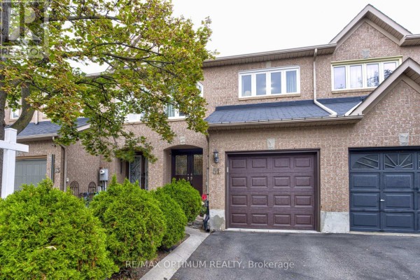 Front view of a brick townhouse with a brown garage door and manicured bushes. - 51 Goldenlight Circle, Brampton