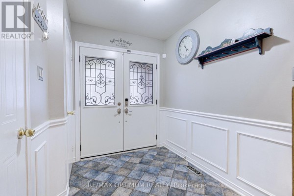 Foyer showing double doors, a coat rack, a clock, and wainscoting on walls. - 51 Goldenlight Circle, Brampton