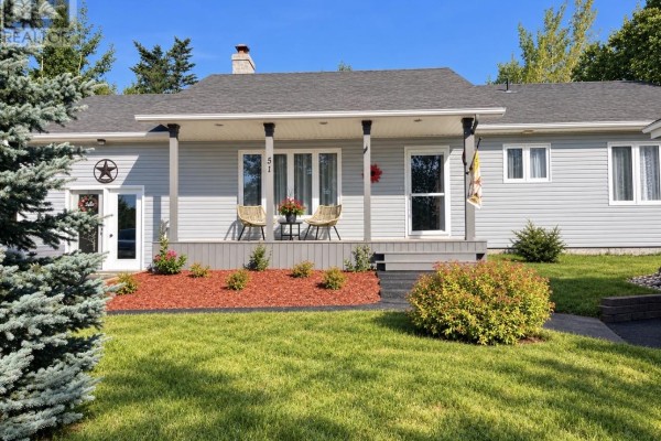 Close-up of the house entrance with a covered porch, two chairs, and decorative landscaping. - 51 Main Street, Hare Bay