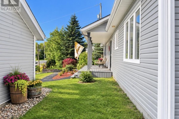 Side view of the house and garage, showing the lawn and flower planters. - 51 Main Street, Hare Bay