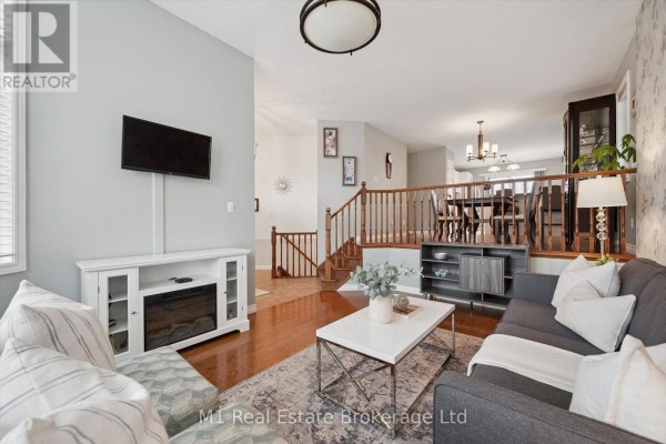 Living room with a sofa and fireplace, viewed towards a staircase and dining area. - 51 Mcgowan Street, Centre Wellington