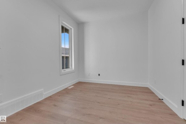 Empty room with white walls, a single window showing the exterior, and light wood flooring. - 51 Meadowgrove Lane, Spruce Grove