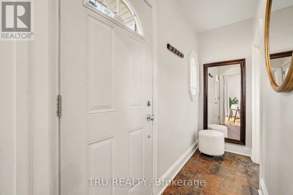 Entrance hall with white door, brown tile floor, oval window, and mirror. - 51 Merritt Avenue, Ottawa