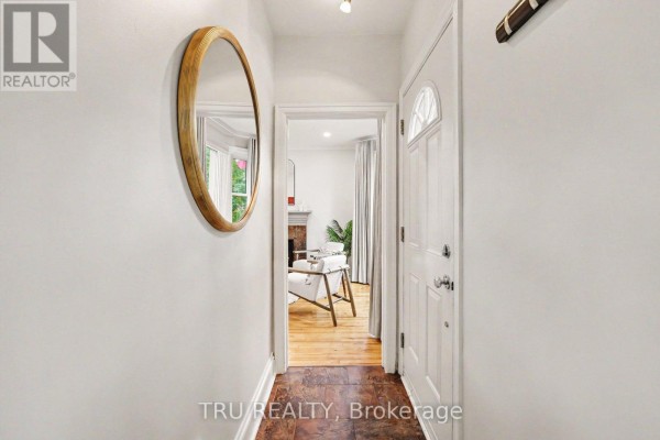 Hallway view into a living room with hardwood floors and a fireplace. - 51 Merritt Avenue, Ottawa