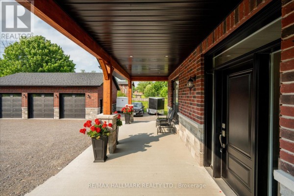 Close-up of the covered front porch of a brick house showing the entrance and garage. - 51 Morrow Road, Trent Hills