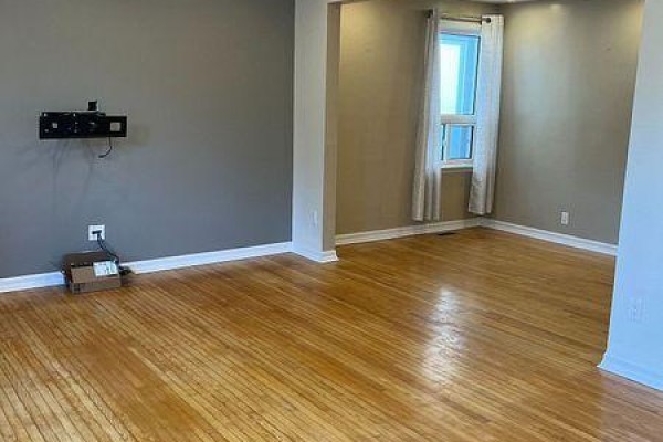 Living room with hardwood floors, grey accent wall with mounted TV bracket. - 51 Northwood Drive, Toronto