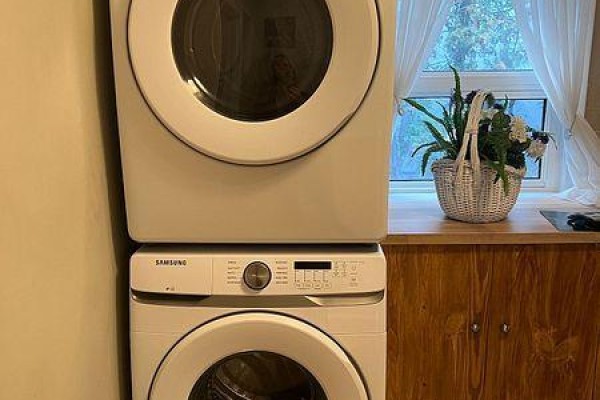 Stacked white Samsung washer and dryer with wooden countertop and basket of flowers. - 51 Northwood Drive, Toronto
