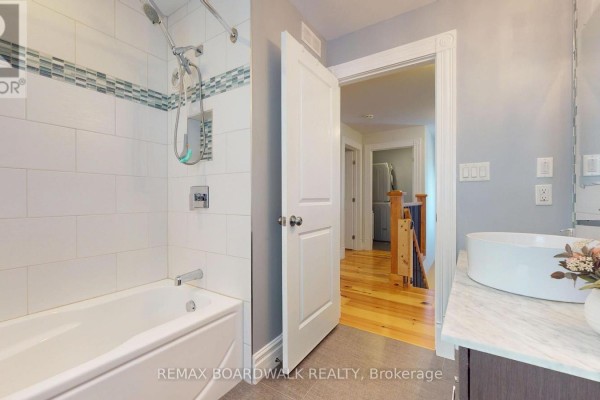 Bathroom with tub, shower, and vessel sink, opening to hallway with washer dryer - 51 Ormond Street Brockville