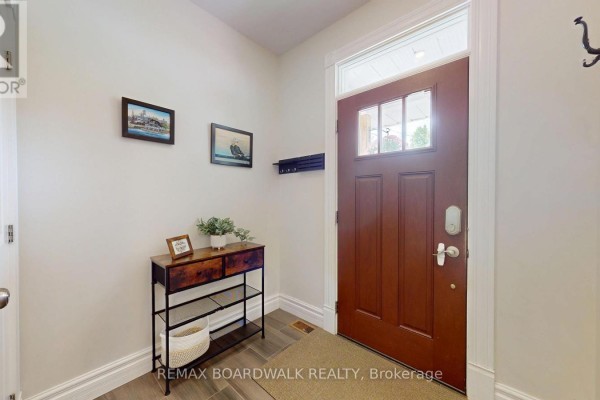 Interior entryway with a wooden door, console table, and coat rack. - 51 Ormond Street, Brockville