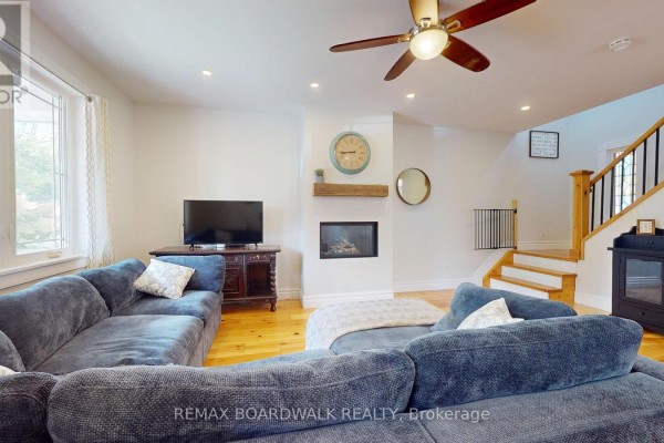 Living room with sectional sofa, fireplace, ceiling fan & staircase - 51 Ormond Street Brockville
