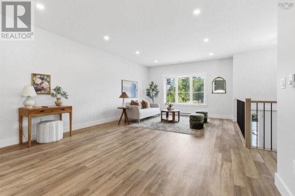 Living room with wood floors, large window, and seating area including a sofa and two ottomans. - 51 Pine Hill Drive, Elmsdale