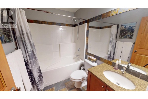 Bathroom with bathtub, toilet, vanity with granite countertop, and mirror. - 51 Rivermount Place Unit# 103, Fernie