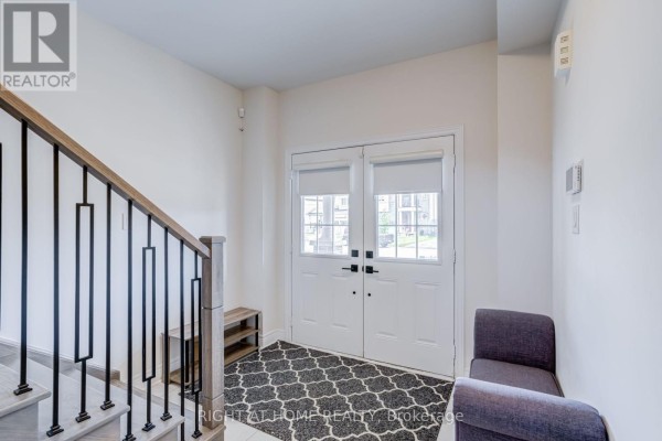 Interior foyer with double glass doors, a dark patterned rug, and two grey chairs. - 51 Rosewell Crescent, Halton Hills