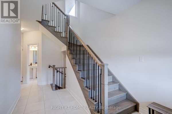 Interior staircase with light wood treads, white risers, and black metal balusters. - 51 Rosewell Crescent, Halton Hills
