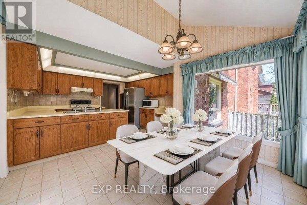 Kitchen with wood cabinets, dining table, and large window - 51 Sanderson Crescent Richmond Hill