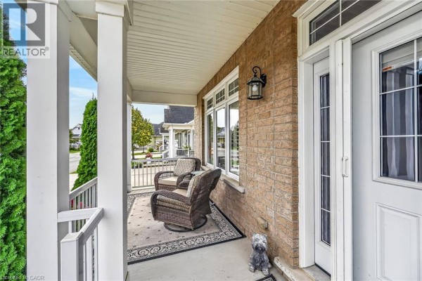 Covered front porch with wicker chairs and a grey dog statue by the door. - 51 Schooner Drive, Port Dover