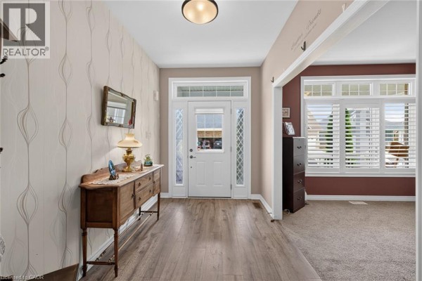 Entrance foyer with a wooden sideboard, a mirrored wall sconce, and light brown wood flooring. - 51 Schooner Drive, Port Dover