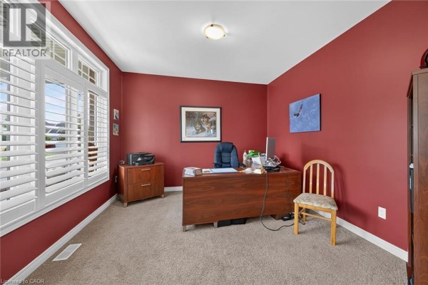 Home office with red walls, a wooden desk, and white plantation shutters on the windows. - 51 Schooner Drive, Port Dover