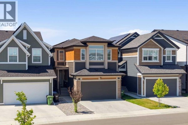 Open concept kitchen with dark cabinetry, a large grey island, and four bar stools. - 51 Setonstone Row Se, Calgary