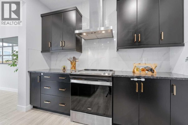 Close-up of black kitchen cabinets with gold hardware and stainless steel appliances. - 51 Setonstone Row Se, Calgary