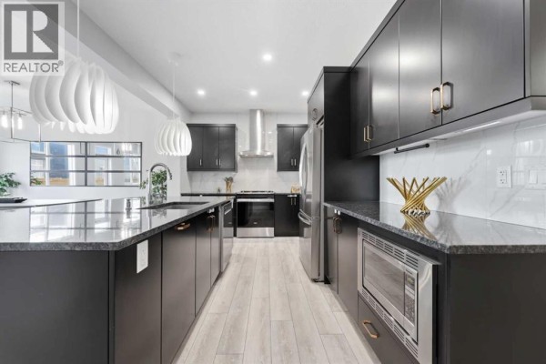 Spacious kitchen with dark cabinets, stainless steel appliances, and a large island with seating. - 51 Setonstone Row Se, Calgary