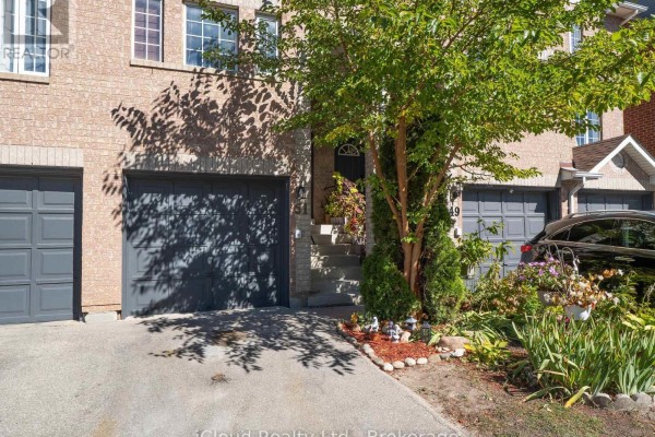 Close-up view of a townhouse entrance with grey garage doors and landscaped front yard. - 51 Spadina Road, Brampton