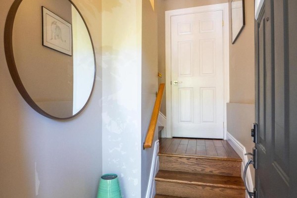 Interior entryway with wooden stairs, a round mirror, and a white paneled door. - 51 Spadina Road, Brampton