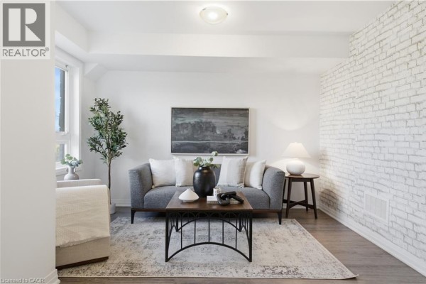 Living room with a grey sofa, coffee table, and a white brick accent wall. - 51 Sparrow Avenue Unit# 96, Cambridge