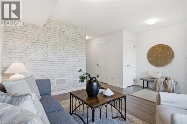 Living room seating area with a sofa, bench, and white brick wall decor. - 51 Sparrow Avenue Unit# 96, Cambridge