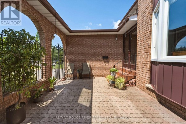Covered arched walkway with brick paving, seating, and potted plants. - 51 Sugarbush Square, Toronto