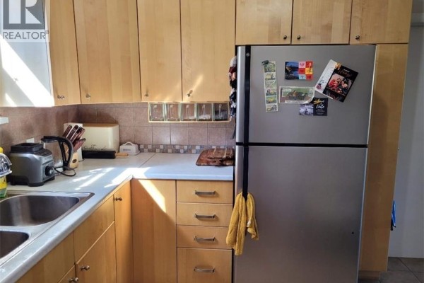 Kitchen counter with stainless steel refrigerator, light wood cabinets, and beige tiled backsplash. - 51 Talbot Street, Kitchener