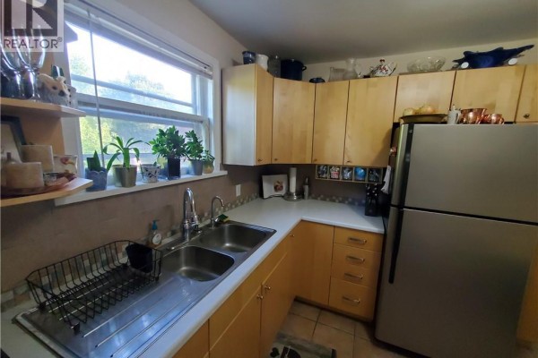 Kitchen area showing sink with faucet, dishwasher, light wood cabinets, and countertop appliances. - 51 Talbot Street, Kitchener