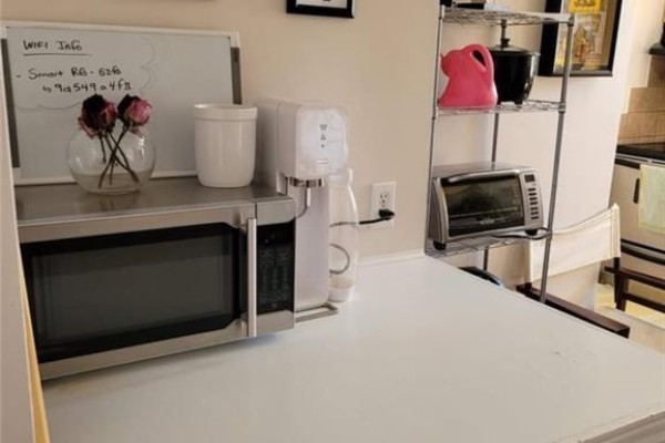 Kitchen counter with microwave, water dispenser, toaster oven, and metal shelving unit with appliances. - 51 Talbot Street, Kitchener