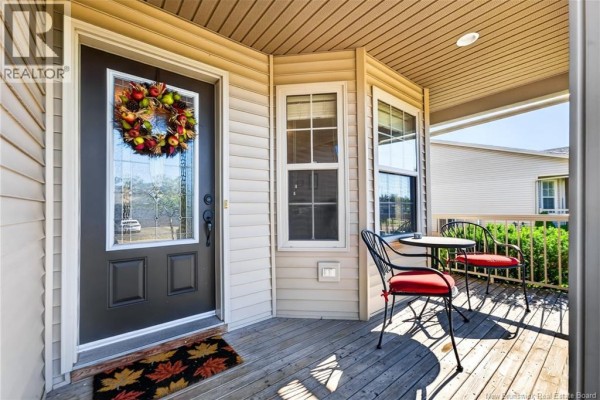 View of the front porch with a dark brown front door, glass inserts, and two chairs. - 51 Thornhill Crescent, Moncton
